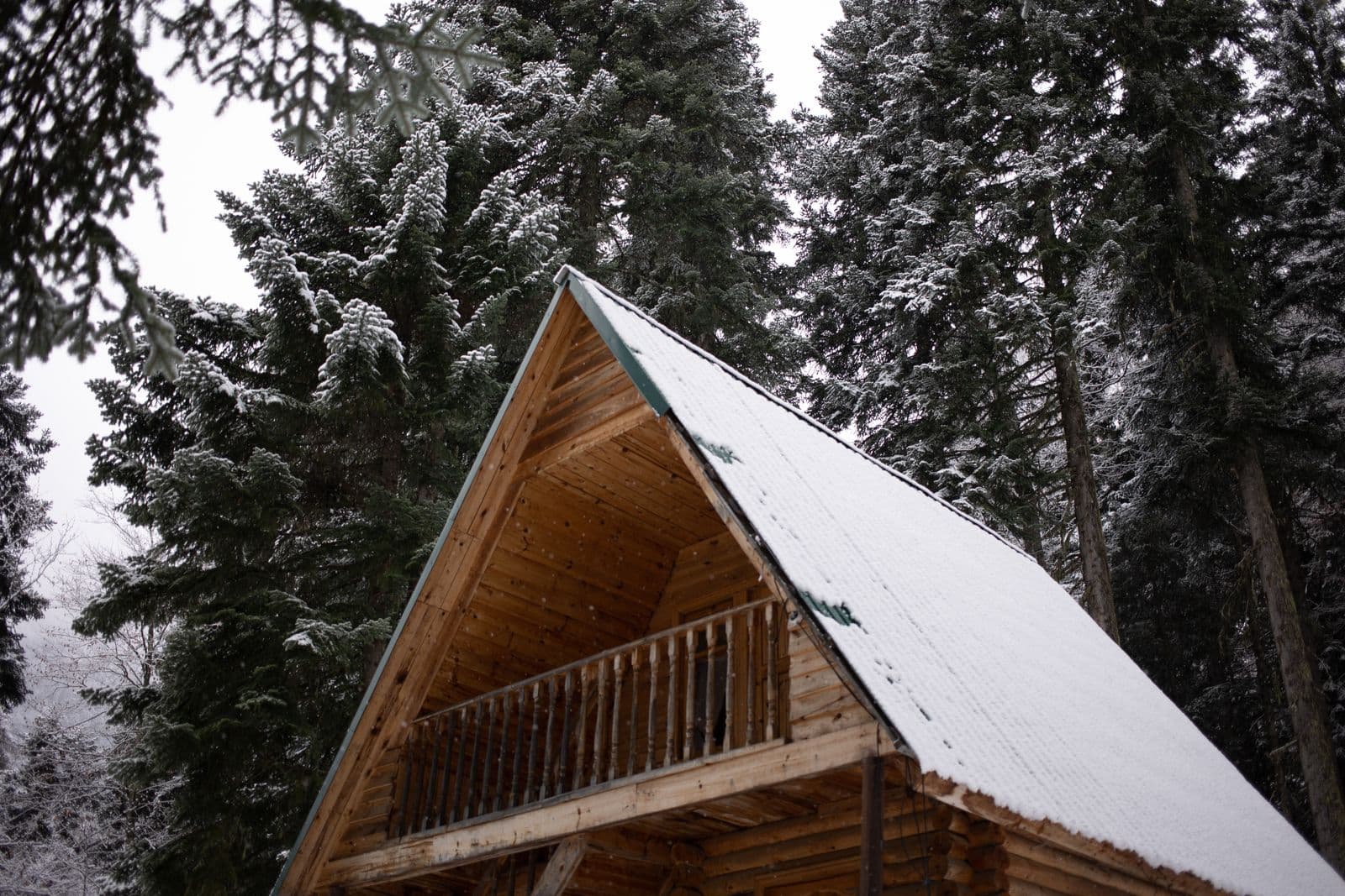 Snow-covered mountain cabin roof among pines in Brian Head, Utah, served by Zenic Industries winter roofing.