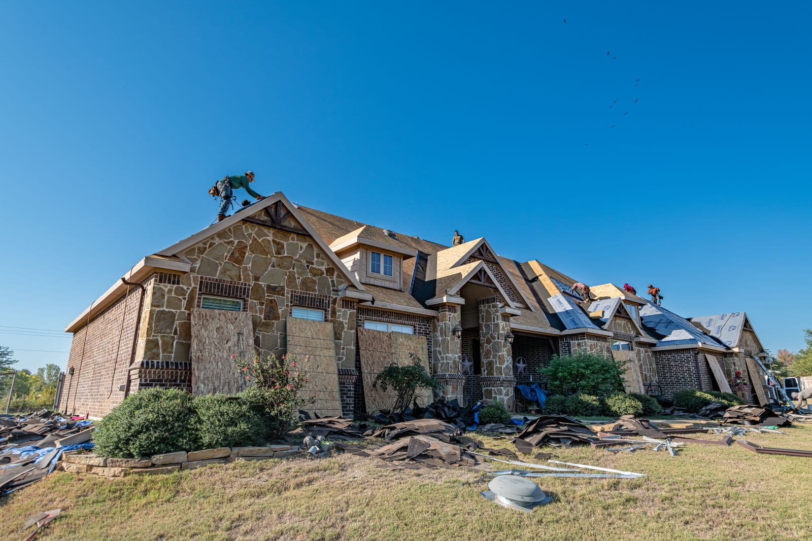 Roofing crew installing a new roof on a Hurricane, Utah home under a clear desert sky, served by Zenic Industries roof replacement.