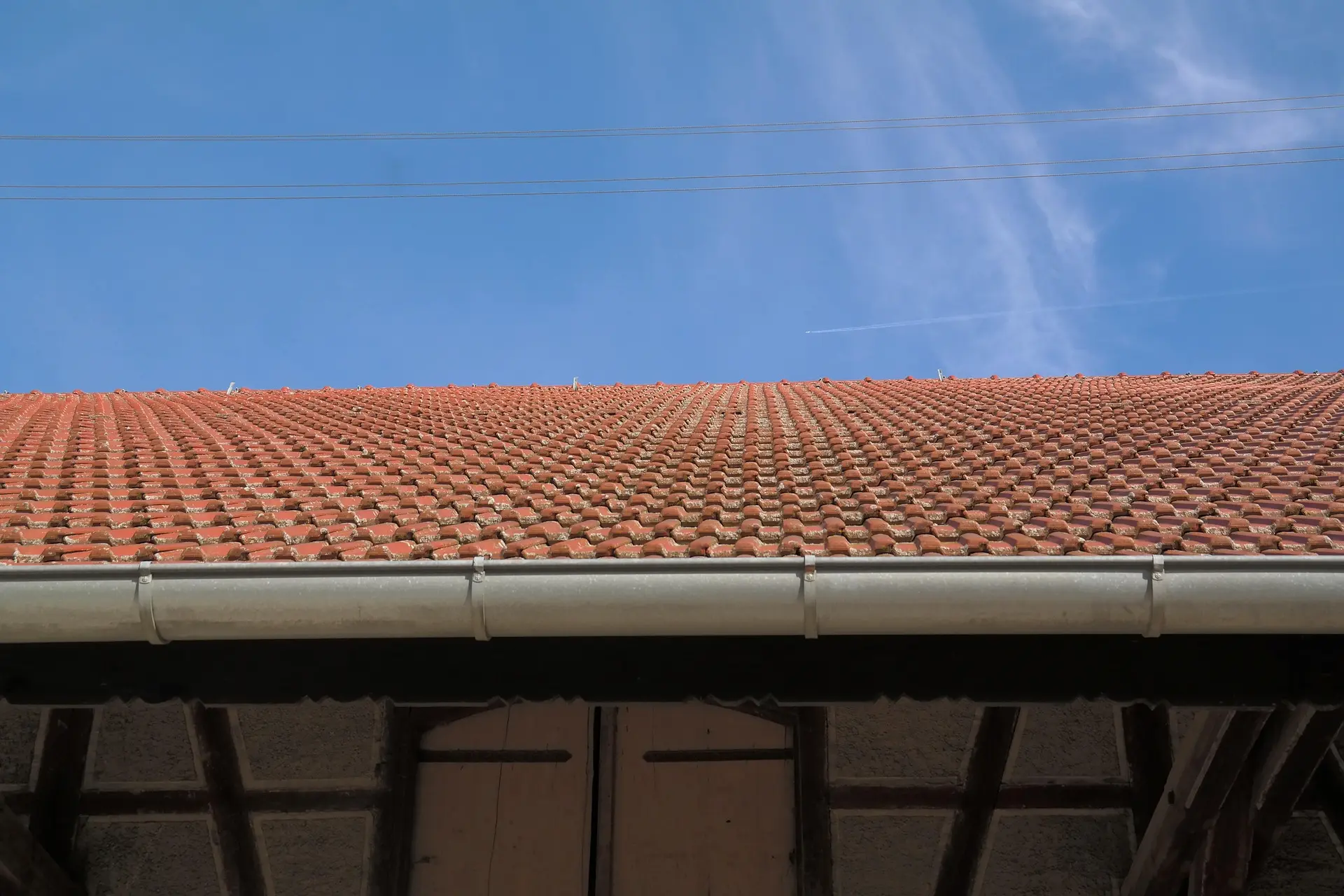 Close-up of terracotta (clay) tile roof with metal gutter under a clear blue sky