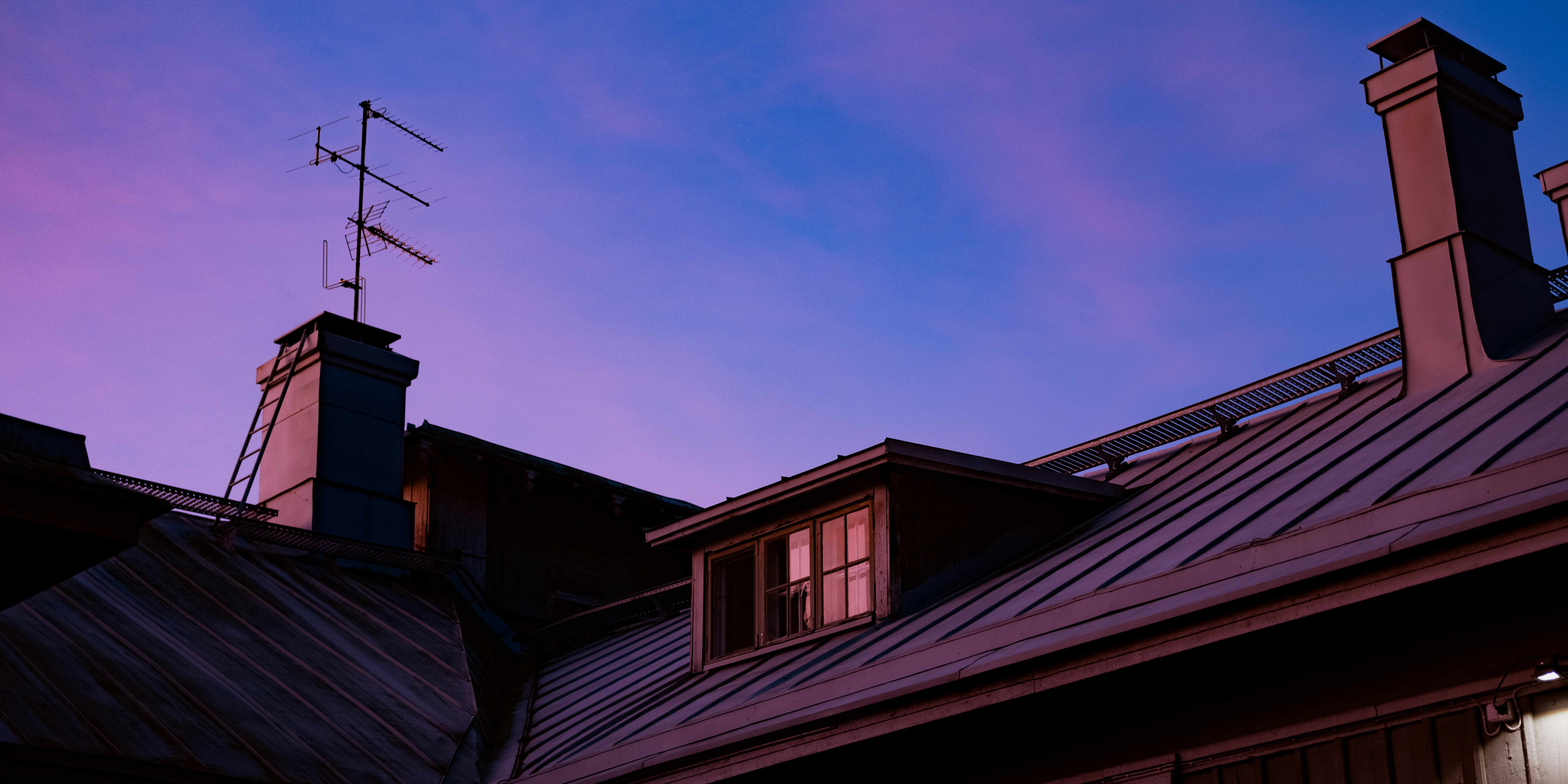 slopes of a metal roof under the dark blue and violet light of a twilight sky